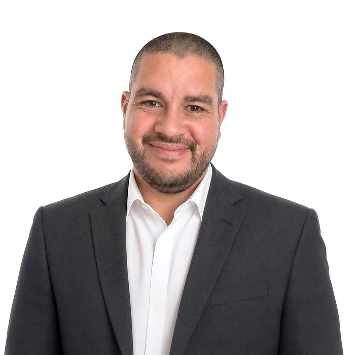 Alexis Caceda im dunkelgrauen Anzug mit weissem Hemd, freundlich in die Kamera blickend
